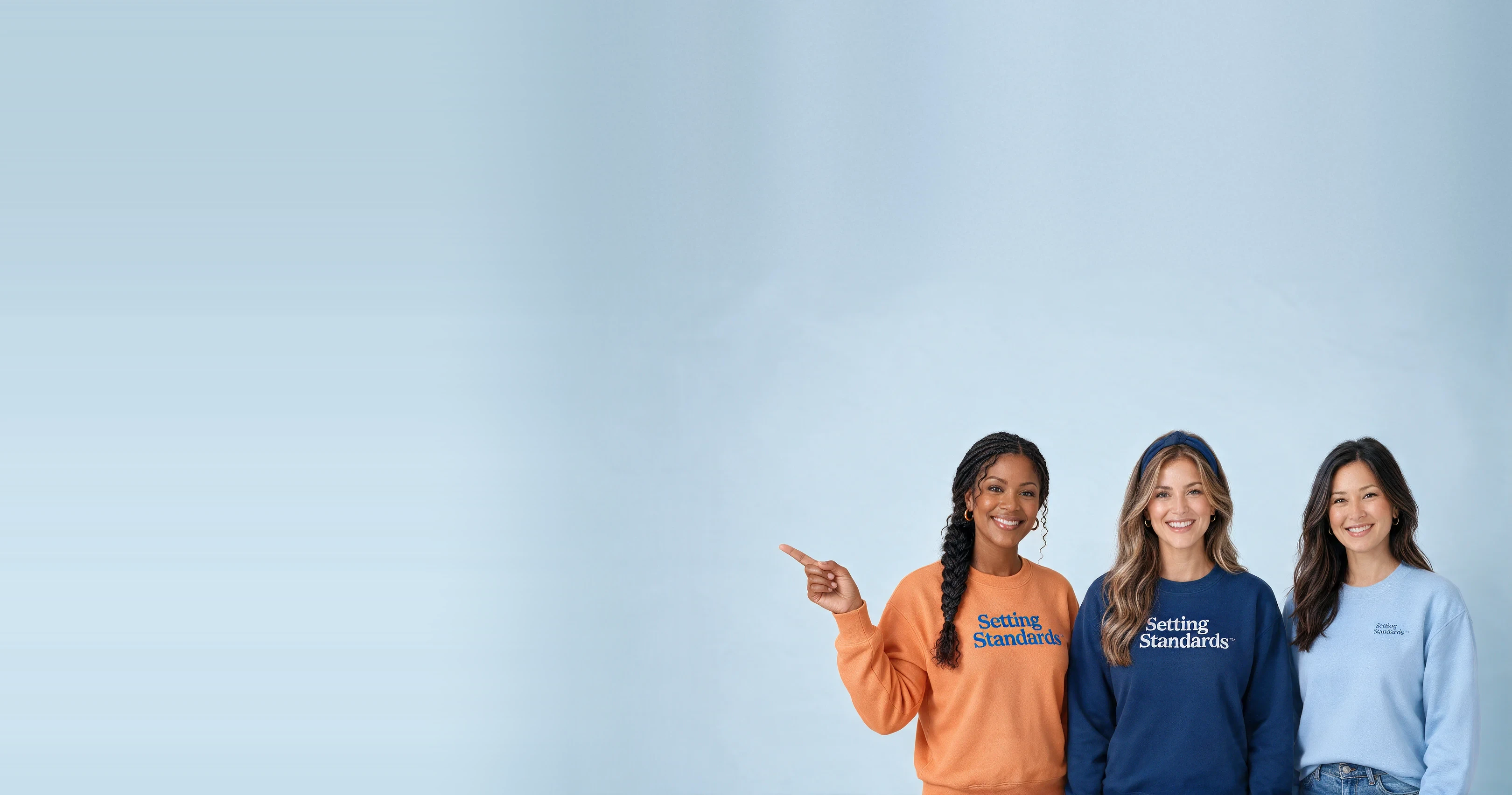 Three Gold Standard ABA team members in Setting Standards sweatshirts, smiling, one pointing toward the words beside them, on a light blue background