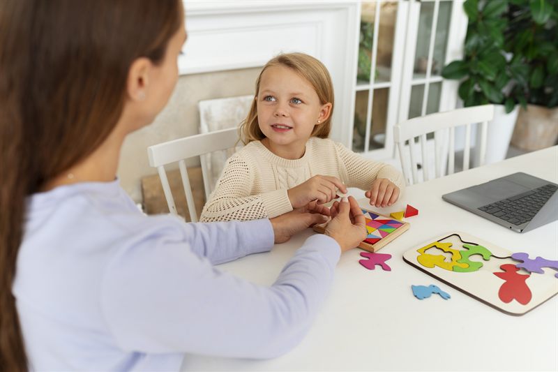 An adult and a child working through a shape puzzle together at a kitchen table