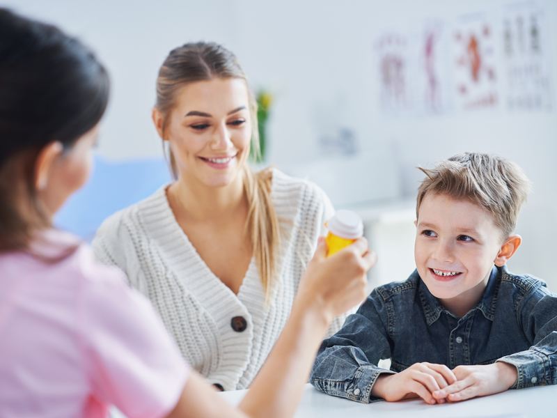 A parent and her son smiling across a desk at a clinician during an appointment